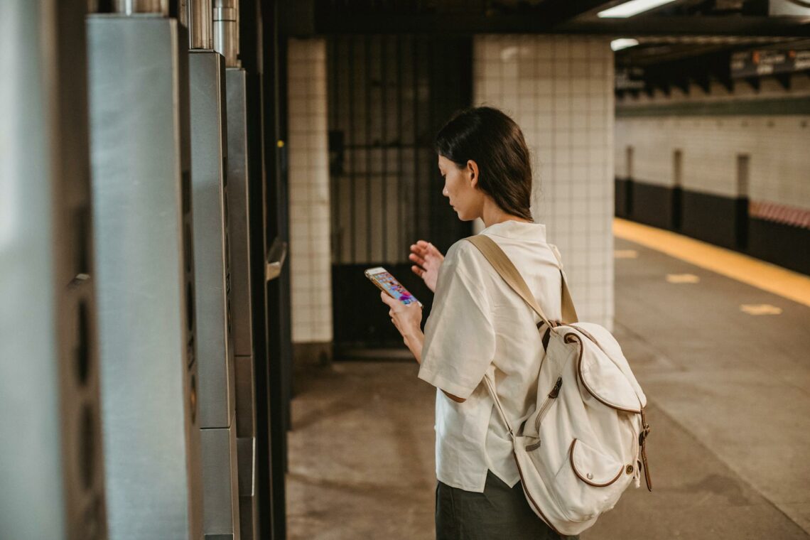 stylish young ethnic woman using smartphone in underground station